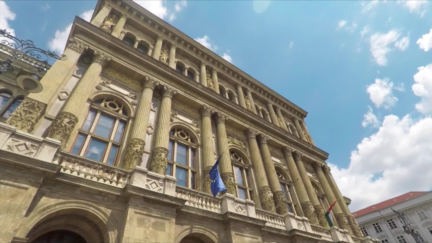 Building Of Hungarian Academy Of Sciences In Budapest, Hungary With European Union And Hungarian Flags On Exterior Facade. low angle