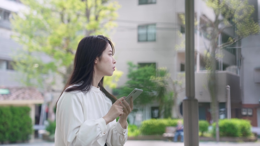 Young asian woman using a smart phone in the town.