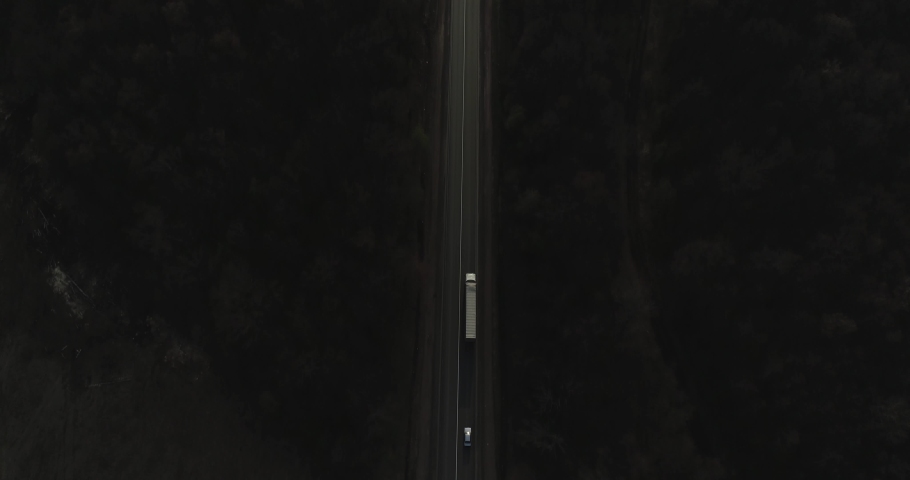 One Semi Truck with white trailer and red cab driving, traveling alone on dense flat forest asphalt straight road, highway top down view follow vehicle aerial footage. Freeway trucks traffic | Shutterstock HD Video #1072668191