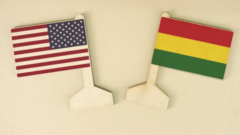 Flags of the USA and Bolivia made of recycled paper on the cardboard table