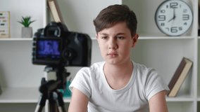 Boy videoblogger filming new vlog video with professional camera at home. Kid vlogger recording video movie for internet. Young blogger talking on video shooting.