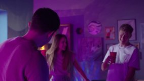 Group of students singing and dancing at home, teenagers having party during coronavirus lockdown, dance together in living room at night. Young friends millenials celebrate birthday holiday.