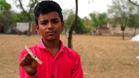 Indian boy staring at pinwheel or hand windmill toy. Boy playing having fun pinwheel. High quality video.