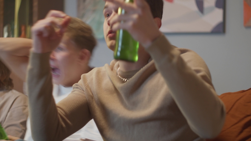 Teenagers friends watching sport tv show, drink at home party during coronavirus, young students man and woman, celebrating happy birthday or Christmas, lockdown, university campus, college