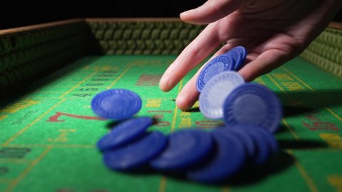 Burbank, CA USA - May 11 2021: This video shows a close up, POV view of a hand tossing a stack of blue gambling chips towards the camera on a craps casino table in slow motion.