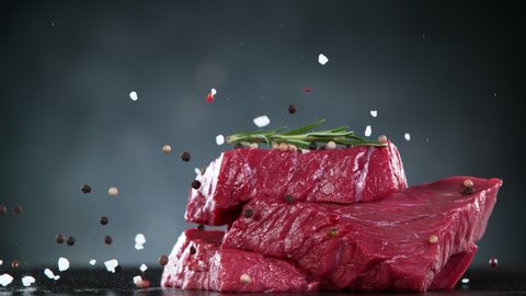 Flying pieces of raw beef steaks falling on table with spice. Filmed on high speed cinema camera, 1000 fps.
