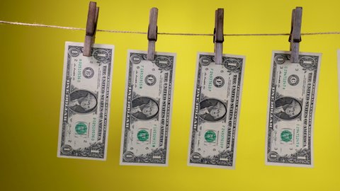 Dollars dry on a clothespin rope on a yellow background. The financial concept of the dollar. One dollar bill on a rope. Money laundering concept.