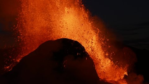 Slow motion Close up of exploding and spewing lava of volcano crater at night