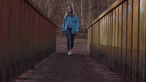 Girl walks one a wooden Bridge and stops in the middle