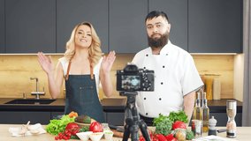 Young woman and man prepare food and host a cooking show. The bloggers stream from kitchen. Healthy food preparation.