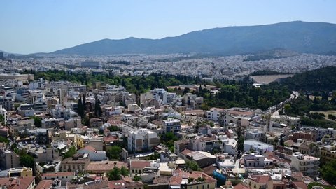 4K Timelaspe aerial video of the Athens city with beautiful houses surrounded by the majestic mountains captured from the viewpoint in the Acropolis, Athens, Greece.
