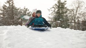 Happy children tobogganing down a snowy hill, slow motion. - Powered by Shutterstock - Get 15% off with code: PIKWIZARD15