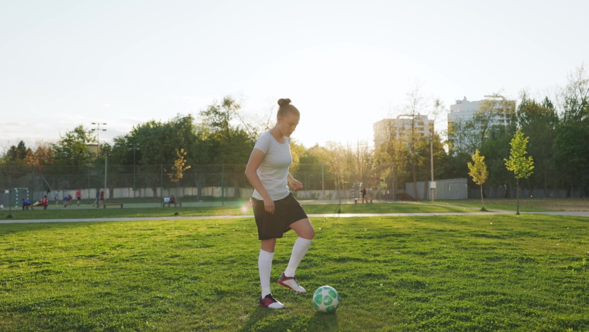 Portrait of woman football soccer player in full growth in the park. Woman in professional uniform juggling with ball. sunset background | Shutterstock HD Video #1072721651