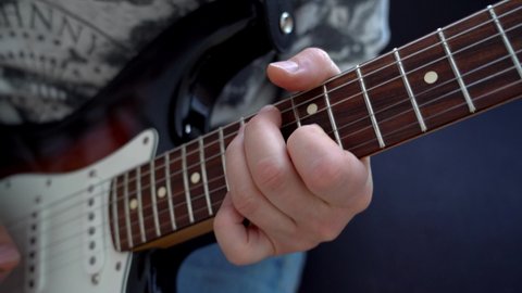 Musician playing the guitar. music artist playing on electric guitar. Fingers holding mediator making melodies, taking chords and notes, beats on guitar. Guitar player school. Close Up.