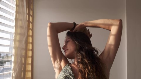 Woman waking up and stretching. girl in morning sunlight shining on her beautiful body. Getting up in the morning in a sexy way. stretching her long feminine body. beautiful gorgeous lady