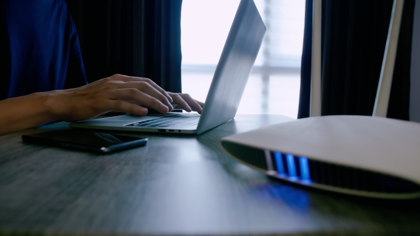 A man is working at home using a modem router, connecting the Internet to his laptop and smartphone. Royalty-Free Stock Footage #1072732142