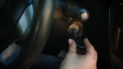 Close-up of woman's hand starting the car. The driver turning car key in the ignition by hand. The beginning of the journey.