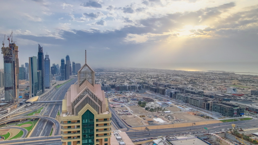 Dubai downtown skyline timelapse at sunset with beautiful city center skyscrapers and Sheikh Zayed road traffic on junction. Top aerial view from tower rooftop. Clouds on the sky. Dubai, United Arab | Shutterstock HD Video #1072734380