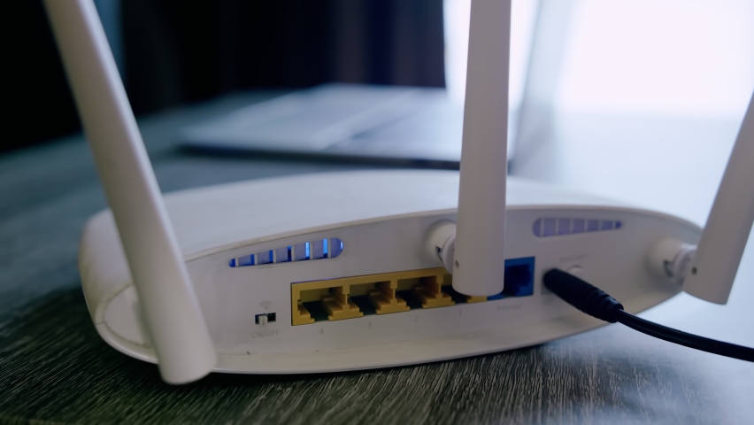 A man is working at home using a modem router, connecting the Internet to his laptop. Royalty-Free Stock Footage #1072735025