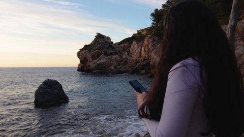 young woman using mobile in a pebble beach