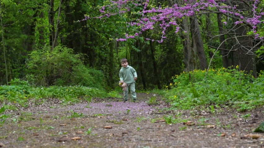  boy holding fluffy toy, walking in the park, on sunny spring day