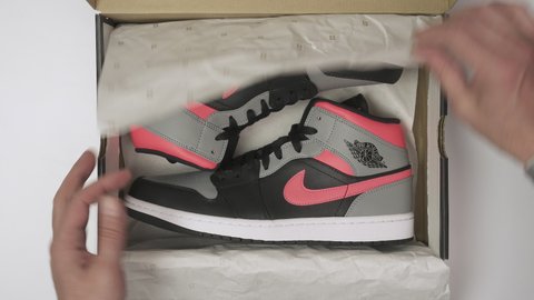 Prague, CZ - 16 May 2021: Unbox a package from Nike arrived 
Air Jordan 1 Mid custom HOT PUNCH Pink Shadow. Retro custom sneaker top view.  Editorial