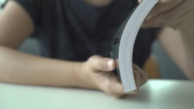 Footage in 4K showing an unrecognizable Asian young woman opening the textbook close up.