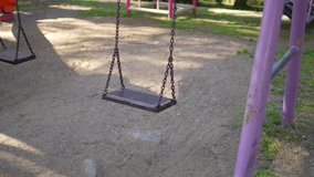 The playing field is empty, the swinging Swing. Empty children's playground in the park during quarantine due to coronavirus covid-19 virus threat. The concept of emergency. Slow motion video.