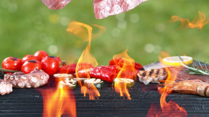 Super slow motion of falling raw tuna steaks on grill grid. 