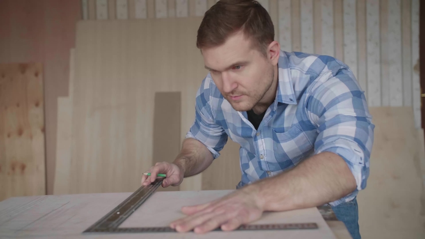 Carpenter makes pencil markings on the blank with the help of a ruler