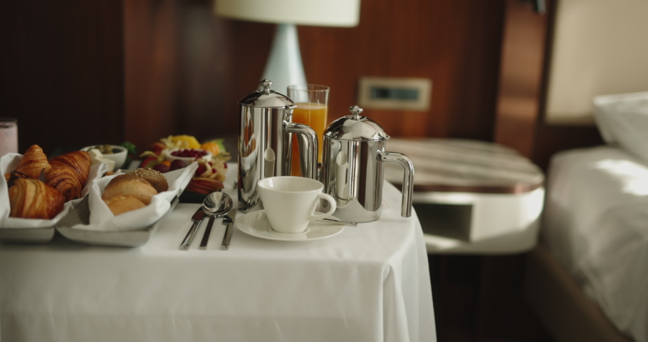 Waiter bringing cart with luxury breakfast into hotel room for customer early in morning. Hotel catering service setting meal 4k footage | Shutterstock HD Video #1072767677
