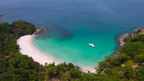 Professional Video 4K. Aerial view shot. Drone camera over white beach sand and sew water clear. Nature video view of beautiful tropical beach and yacht at sea. Freedom beach. At Phuket, Thailand.