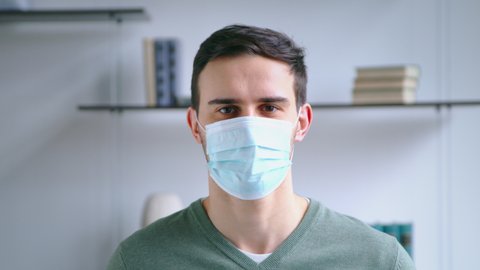 Young man taking off medical mask and smiling while looking at camera. Lifestyle concept