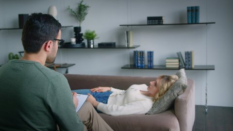 A psychotherapist conducting meditation for a patient on a couch in an office. Patient meditating on a couch