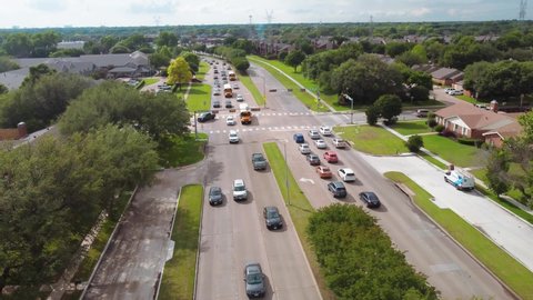 A aerial drone video of flying over traffic in a neighborhood in Plano Texas. While the drone moves towards cars and school buses it pans up for a look at the dallas texas stormy spring skies.