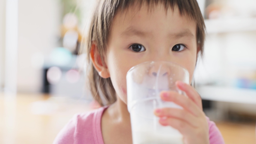 Cute little girl holding a glass and drinking milk Little baby smiling at the camera at home with hands stretched out to the camera Royalty-Free Stock Footage #1072788143