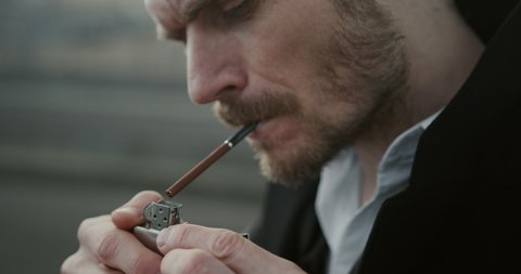Close-up of a cigarette. A man smokes a cigarette on the street, he inhales the fragrant smoke and relaxes. Nicotine fills the lungs, but the man prefers not to think about it.