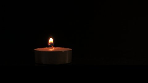 A tealight candle burning on a black background