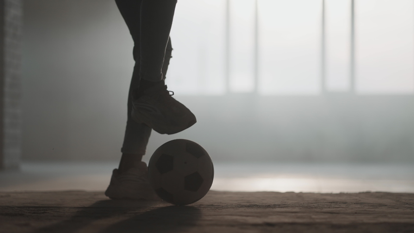 The silhouette of a football player training in an underground parking lot in the sun and rising dust. The concept of the success of sporting aspirations and perseverance. Freestyle Football | Shutterstock HD Video #1072791227