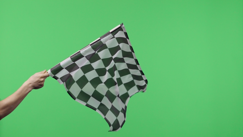 Male hand holding and waving checkered race flag in slow motion against green screen background. Silk black and white checkered flag finish start race. Victory, achievement, success and sport concept. Royalty-Free Stock Footage #1072793012