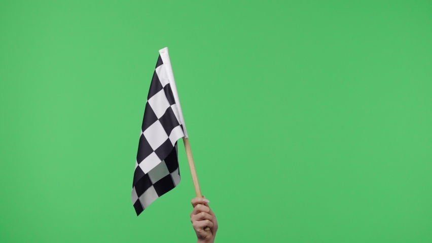Female hand holding and waving checkered race flag in slow motion against green screen background. Victory, achievement, success, sport concept. Silk black and white checkered flag finish start race. Royalty-Free Stock Footage #1072793015