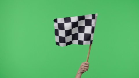 Female hand holding and waving checkered race flag in slow motion against green screen background. Victory, achievement, success, sport concept. Silk black and white checkered flag finish start race.