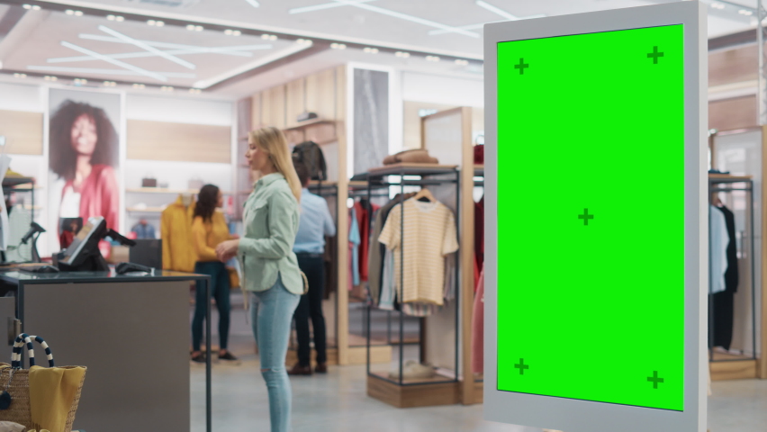 Customer Using Floor-Standing LCD Touch Display with Green Screen Chroma Key Mock Up while Shopping in Clothing Store. She is Checking for Information, Looking at a Floor Plan, Choosing Items Online. Royalty-Free Stock Footage #1072795244