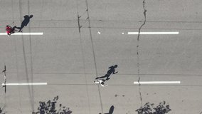 Aerial top down group of people running city marathon, onlooker recording video with smartphone, their shadows on asphalt road. Healthy lifestyle. Outdoor activity. Concept of sport