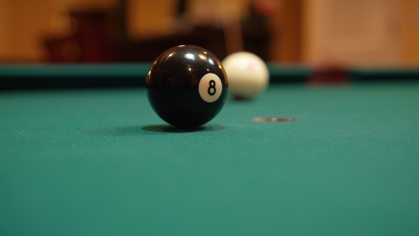 Man Playing 8 Ball Pool Gets Down and Shoots Solid Black Eight Ball into Pocket Past Camera using Draw or Backspin and Wooden Cue Stick on a Brunswick Table with Green Felt, Playing Billiard Bar Games | Shutterstock HD Video #1072796984