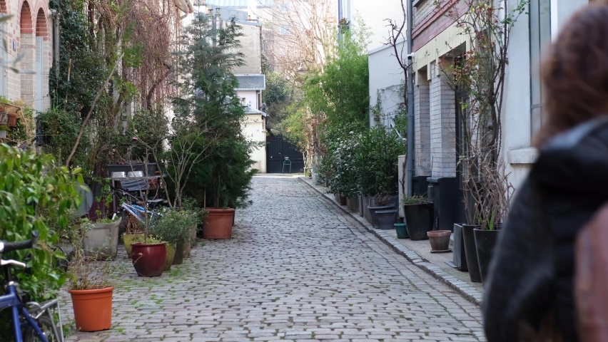Caucasian young woman running away in a small street in Paris, France