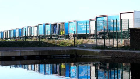 WIDNES, CHESHIRE, UNITED KINGDOM - CIRCA APRIL, 2021: Rear side of Hermes delivery firm trucks car park and lorry reflections on water.