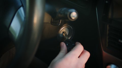 Close-up of man's hand starting the car. The driver turning car key in the ignition by hand. The beginning of the journey