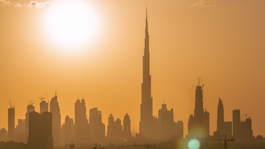Sunset with skyline of Downtown Dubai in the evening timelapse. Beautiful skyline of modern skyscrapers of city built in the desert. Aerial view from building near airport
