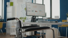 Interior of cozy light company room with wheelchair parked near desk and in empty office room. Modern stylish chairs and desktop computer, all ready for employees, spacious office of economic working - Powered by Shutterstock - Get 15% off with code: PIKWIZARD15